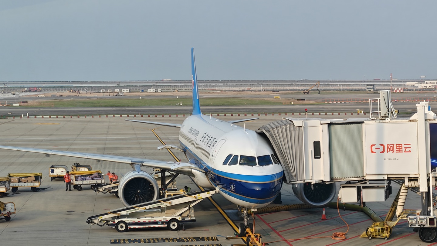 A passenger aircraft connected to a jet bridge on an airport apron