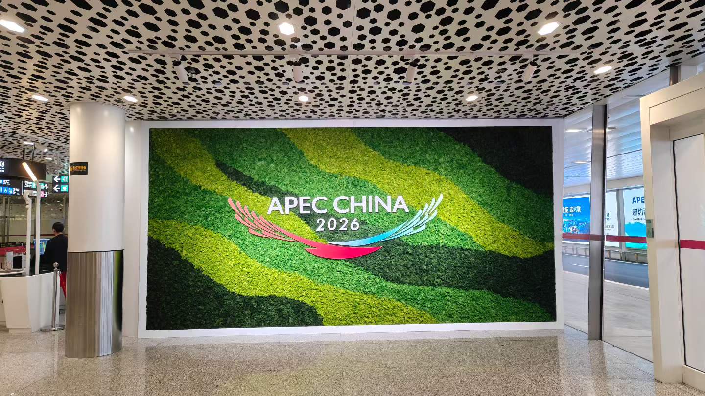 A large green APEC China 2026 display inside an airport terminal