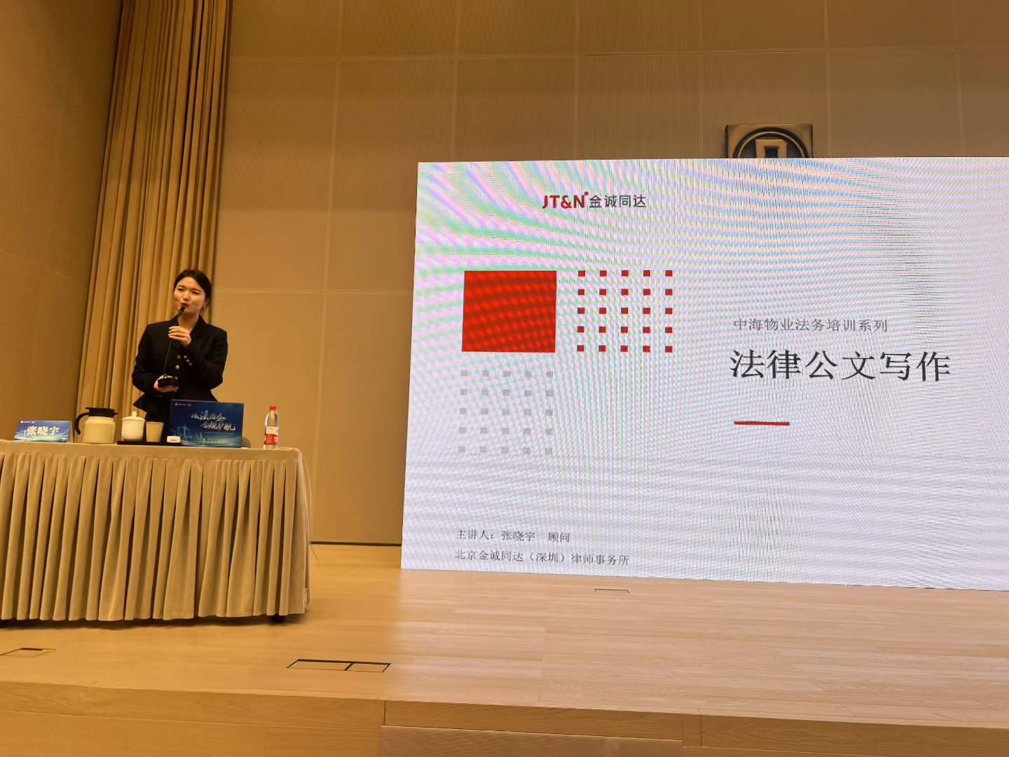 Kelly Zhang speaking beside a projection screen titled Legal Document Writing for a China Overseas Property legal training session