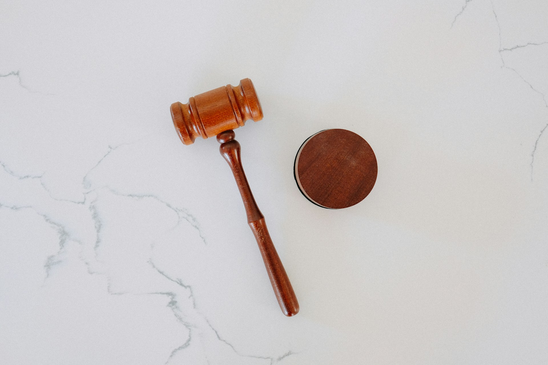 A wooden judge's gavel and sound block resting on a white marble surface